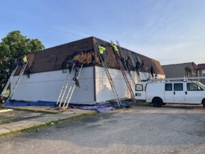 Multiple roofers removing old shingles from a commercial building roof, a service by Mp painting and roofing LLC in Dayton, OH