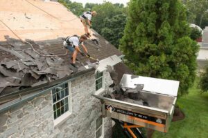 Roofers efficiently removing old shingles from a residential roof using an Equipter debris management system by Prescott Roofing and Masonry in Carnegie, PA.