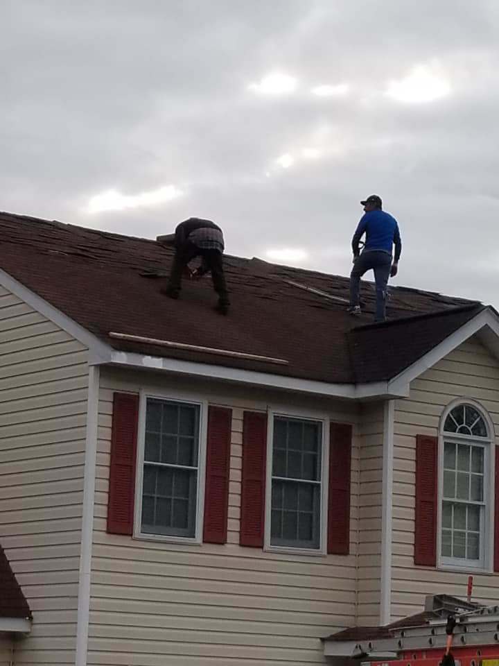 Two roofers working on a residential house roof, performing repairs or installation for Professional Contractor RVA in Richmond, VA.