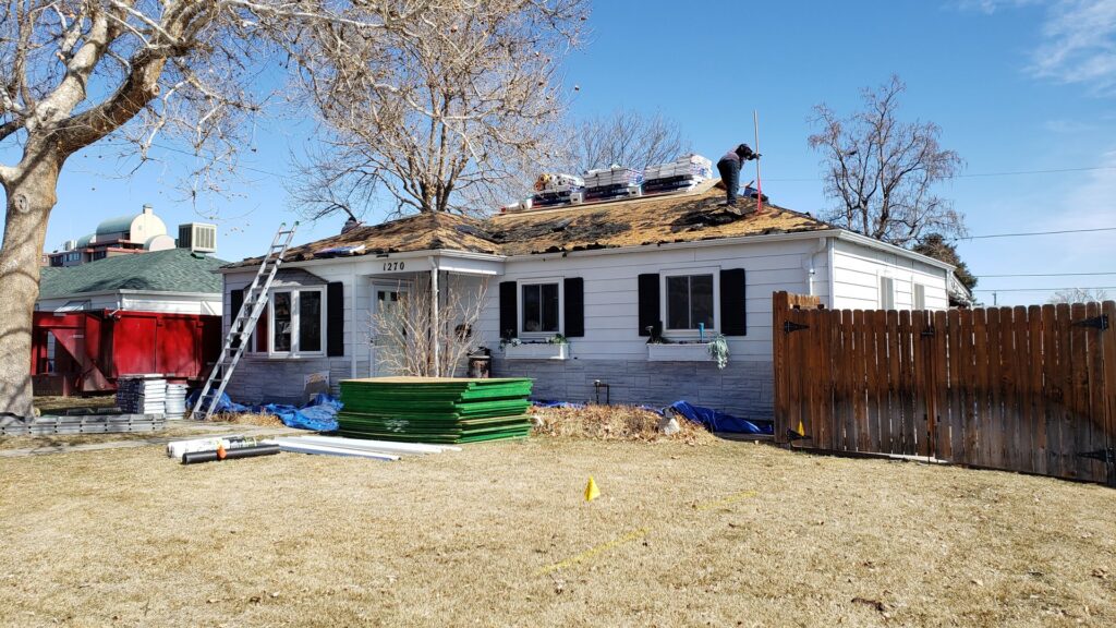 Roofers installing a new roof on a house with ladders and materials on site for Roof Maxx of S Aurora, CO