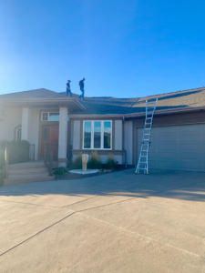 Two professional roofers working on a residential roof with a ladder at Quick Roofing Colorado in Castle Rock, CO.