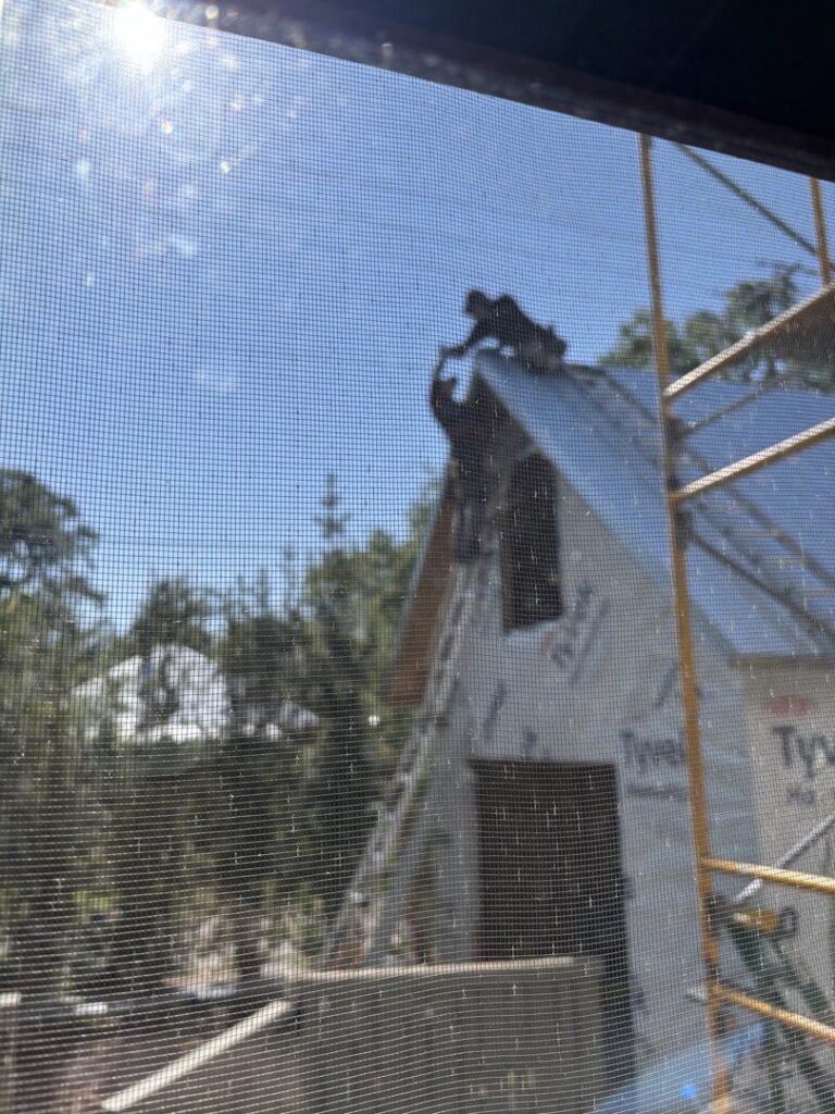 Construction workers on a roof, with Tyvek wrap visible, indicating a roofing project in progress by Hastings Roofing Service Inc. in Orlando, FL.