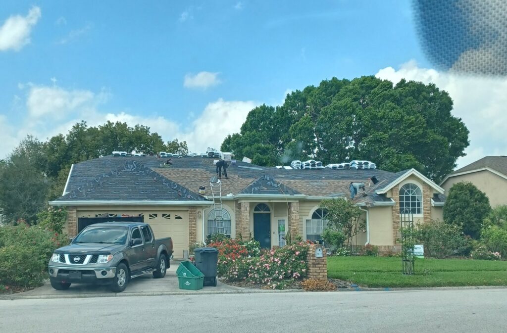 A roofing crew actively installing new shingles on a residential home, managed by Hastings Roofing Service Inc. in Orlando, FL.