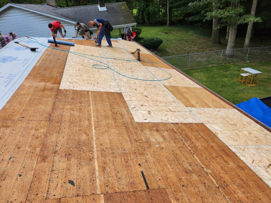 A roofing crew working on plywood and underlayment installation by Rock Solid Const in Youngstown, OH.