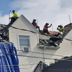 A roofing crew from Manny's Sb Construction Inc removing old shingles from a residential roof in Goshen, NY.