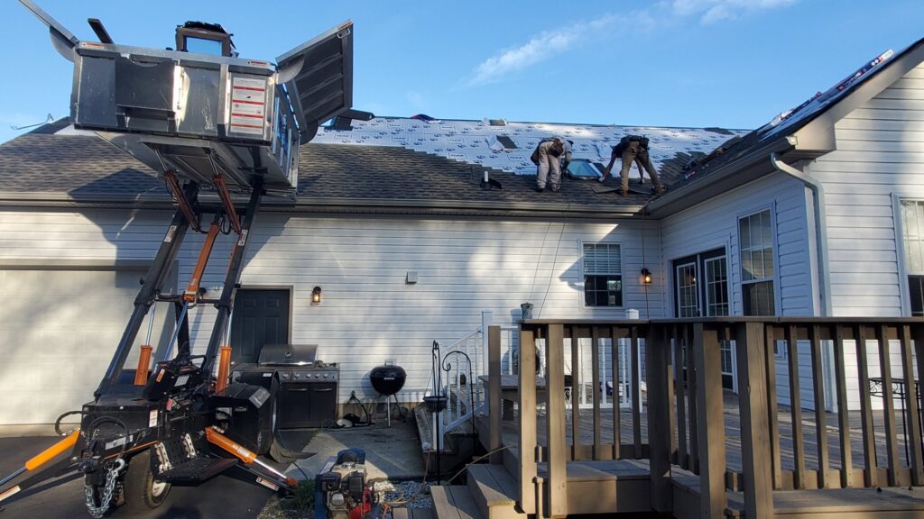 A roofing crew using a debris lift during a roof replacement project for Bayside Exteriors in Lewes, DE.