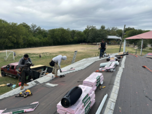 Workers installing new roofing shingles on a residential property, a service provided by Total Improvements LLC in San Antonio, TX.