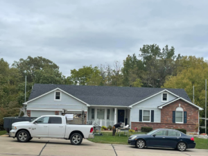 A house undergoing a roofing job with a dumpster and truck, provided by Remodeling by Simplified Solutions in Saint Charles, MO