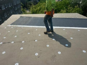 A worker performing roofing repair or installation on a flat roof by Paramount Development in Milwaukee, WI.