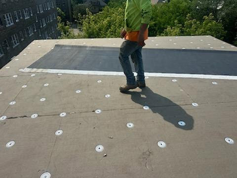 A worker performing roofing repair or installation on a flat roof by Paramount Development in Milwaukee, WI.
