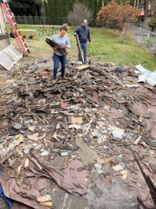 Two workers from Just Junk It standing on a large pile of roofing shingles and debris, ready for removal in Lancaster, PA.
