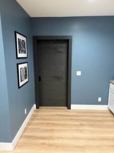 A room with blue walls, a dark door, and wooden flooring, showcasing interior work by Dakota Small Jobs in Sioux Falls, SD.