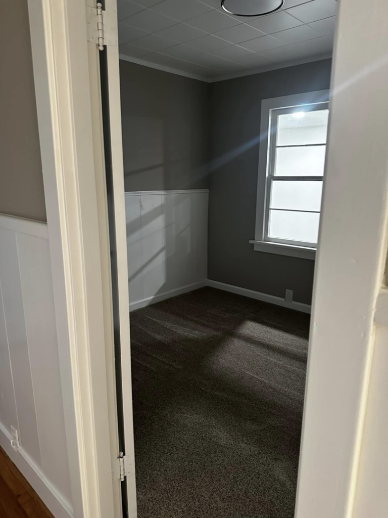 An empty room featuring new carpet installation, wainscoting, and fresh paint by A to Z Remodeling llc in Gresham, OR.