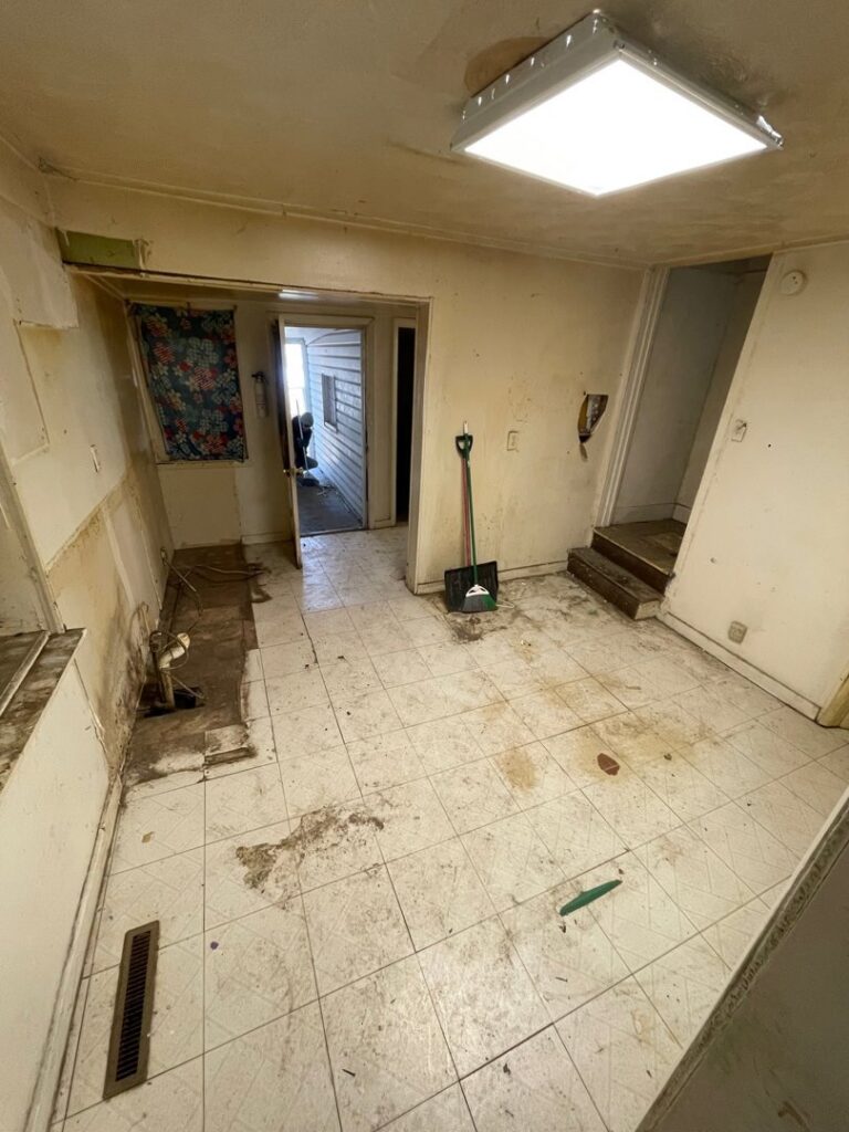 A room with some debris on the tiled floor, showing a space after a cleanout or demolition by Removall Residential and Commercial Cleanout Services in York, PA.