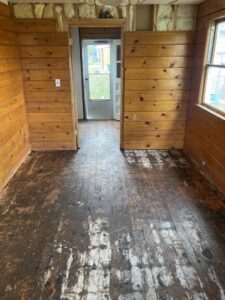 A room undergoing demolition with damaged wood flooring and exposed walls by Asbestos Abatement, Inc in Englewood, CO.