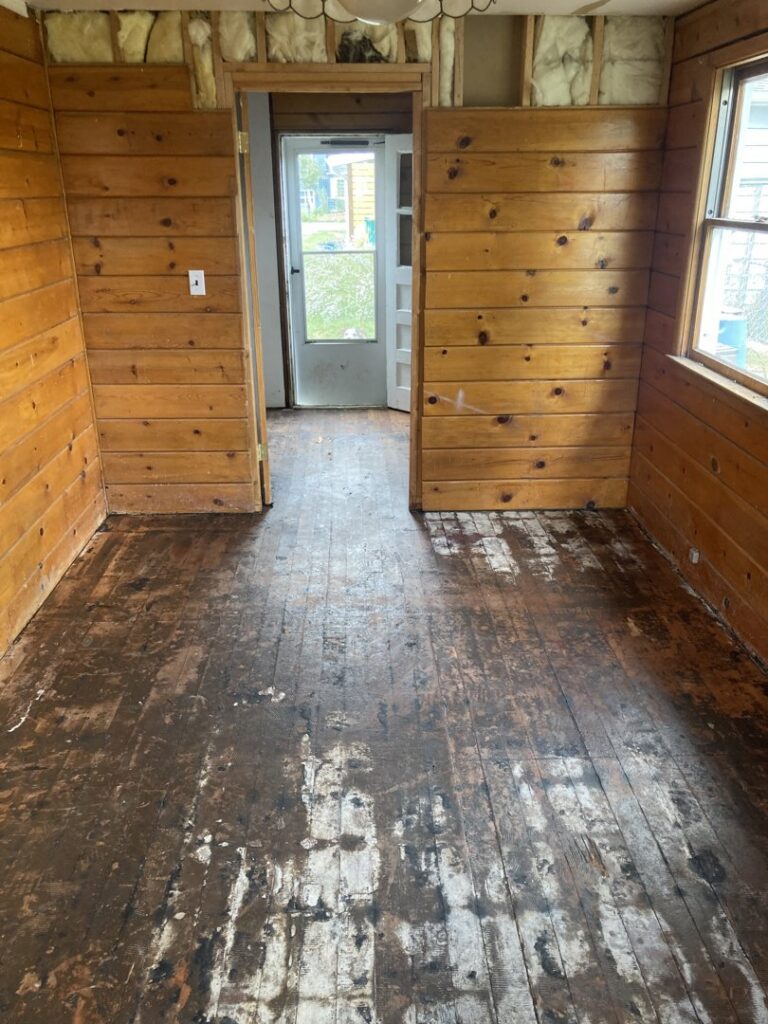 A room undergoing demolition with damaged wood flooring and exposed walls by Asbestos Abatement, Inc in Englewood, CO.
