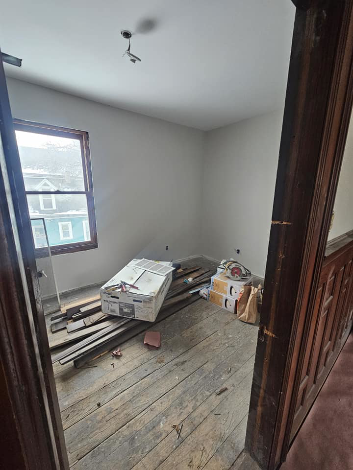 An interior room with old wooden flooring and construction debris, showing renovation prep by Done Well Home Improvement LLC in Buffalo, NY.