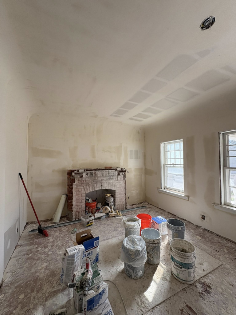 An interior room undergoing drywall repair and painting preparation with a brick fireplace by EJL Construction, LLC in Roswell, NM.