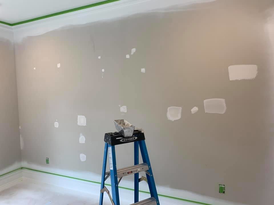 A room with multiple drywall patches and a ladder, prepped for painting by Walrus Rock Construction LLC in Pacific, MO.