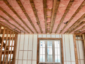An unfinished room with fiberglass insulation in the ceiling and spray foam insulation on the walls by Spray Foam Art-Insulation in Stamford, CT.