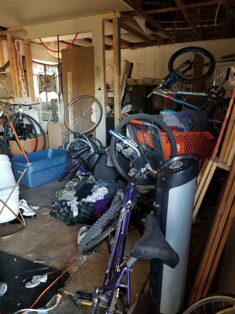 A room heavily cluttered with multiple bicycles, boxes, and various items, representing a junk removal job by Affinity Bio Solutions in Phoenix, AZ.
