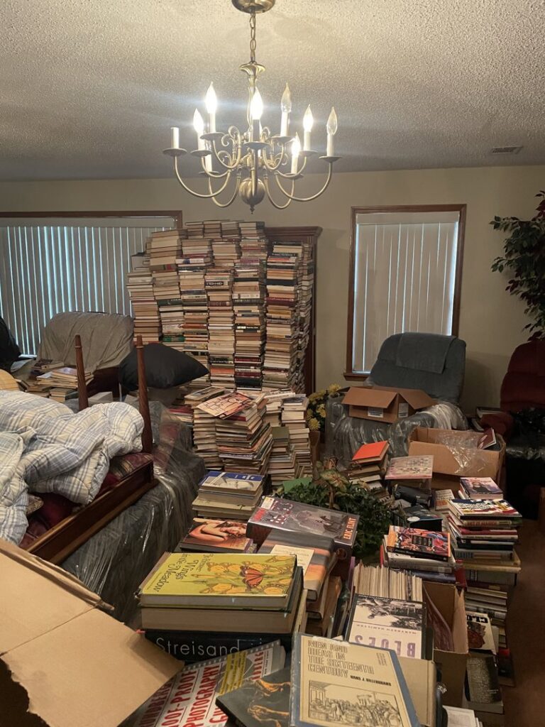 A room completely filled with stacks of books and boxes, indicating a large cleanout job by AAA Rousse Junk Removal Services Inc of Florida in Tampa, FL.