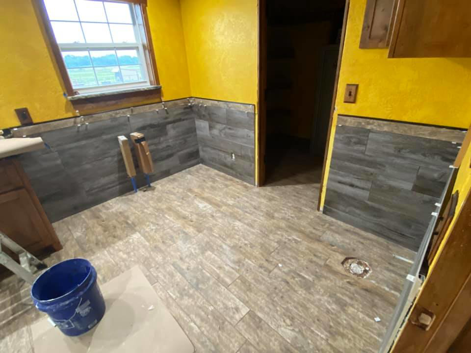 Room with floor and partial wall tile installation in progress by Quality Craftsman Construction in Longwood, FL.