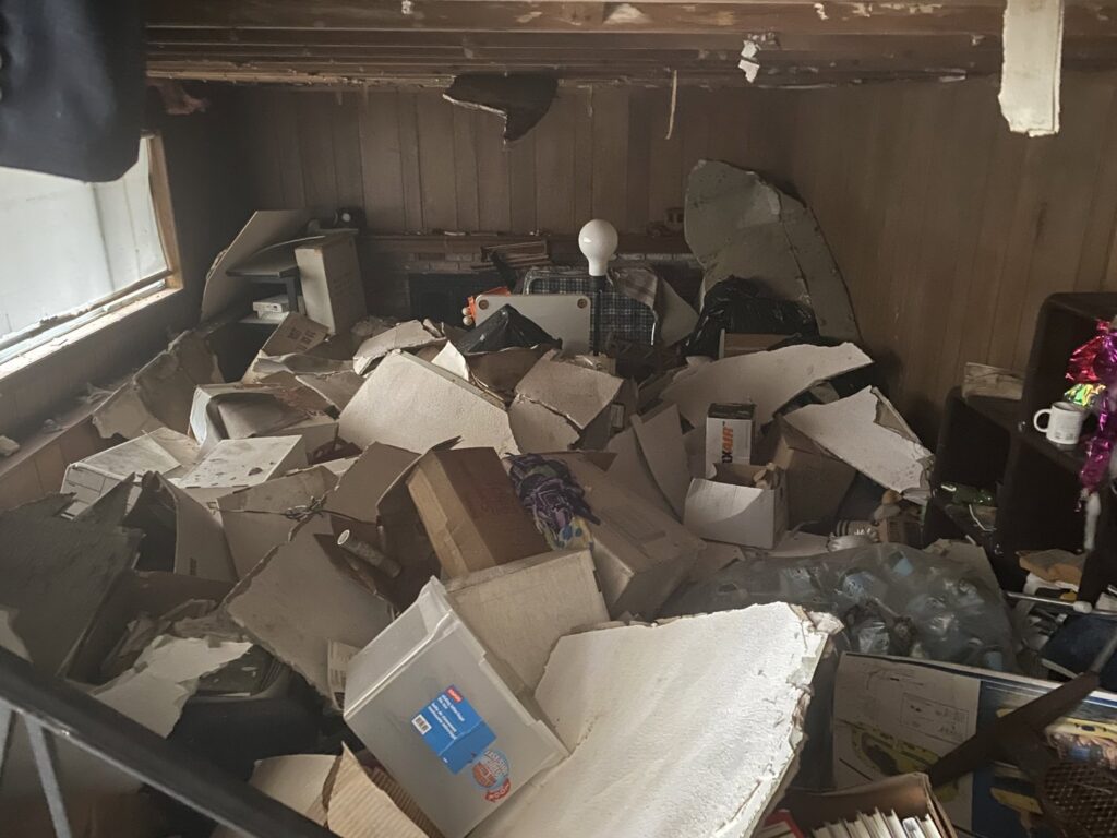 A room completely filled with cardboard boxes and debris, requiring extensive junk removal by Trash King LLC in Derry, NH.