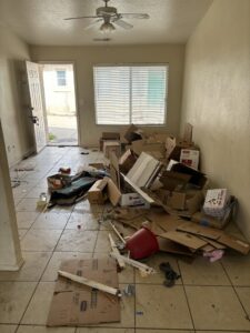An indoor room filled with cardboard boxes and debris, indicating a cleanout job by YEE-HAul Trash Removal in St. George, UT.