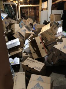 A room completely filled with collapsed cardboard boxes, indicating a large cleanout job for Hudson's Trash Removal, LLC in Great Falls, MT.