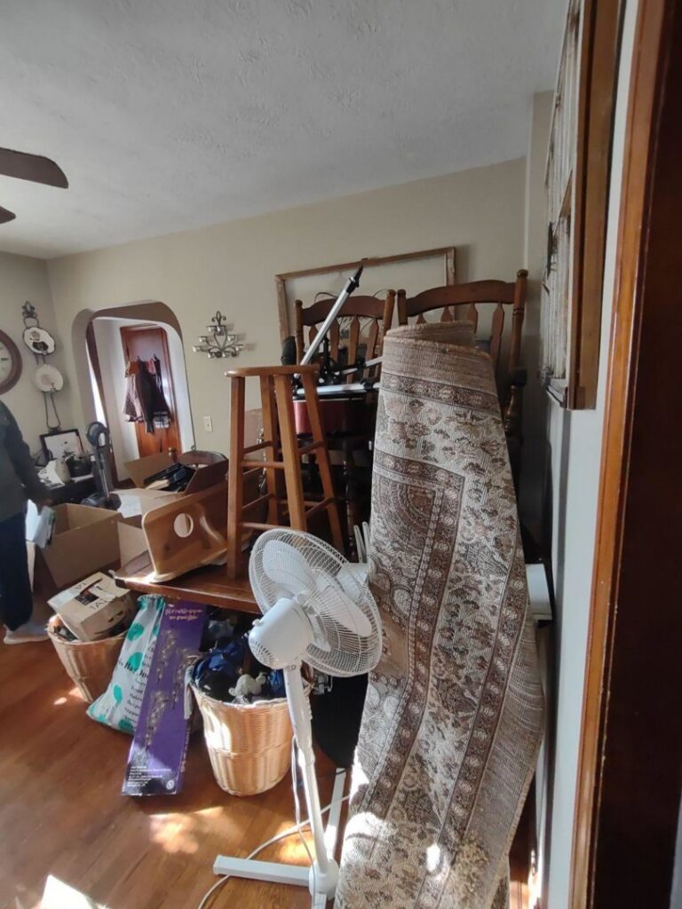 A room filled with furniture, rolled rugs, and boxes, indicating a decluttering or cleanout project by 1-800-Declutter in Cincinnati, OH.