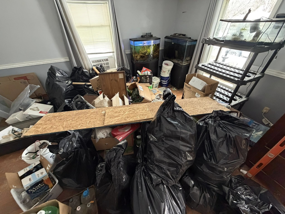 A room filled with black trash bags and boxes, ready for junk removal by Hometown Hauling 802 in Milton, VT.