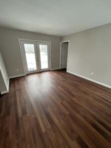 A renovated room featuring new hardwood flooring and modern French doors installed by Rock Solid Construction in Rochester, NY