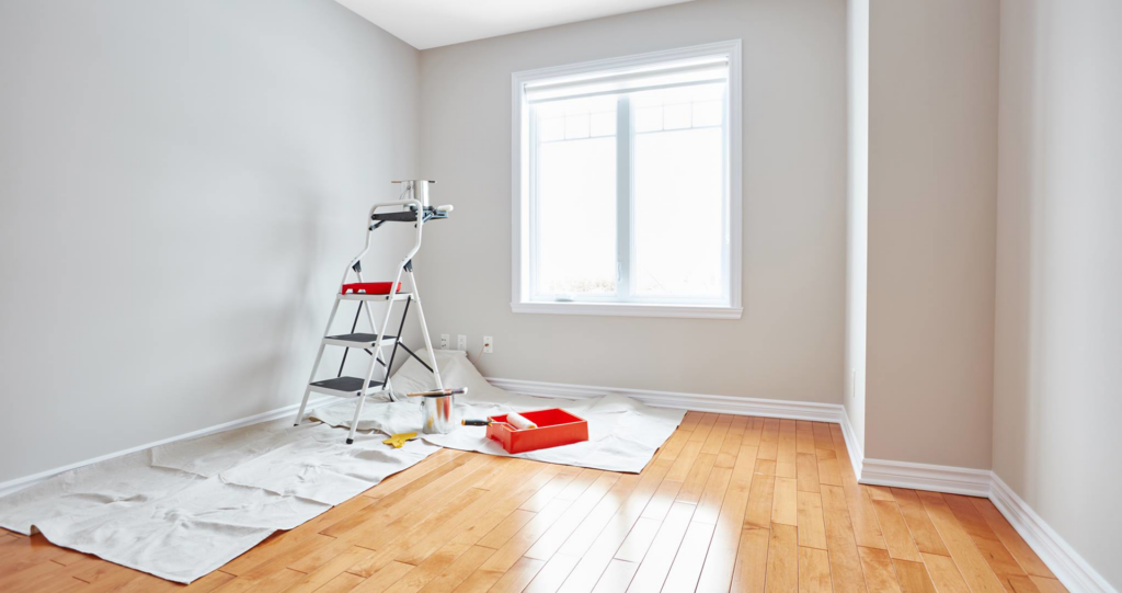 A room prepared for painting with a ladder, paint tray, and drop cloths by Brauny Home Services, LLC in Arvada, CO