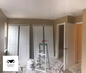 A room prepared for painting with a ladder and paint buckets, part of handyman services by Waterbury Drywall in Waterbury, CT.