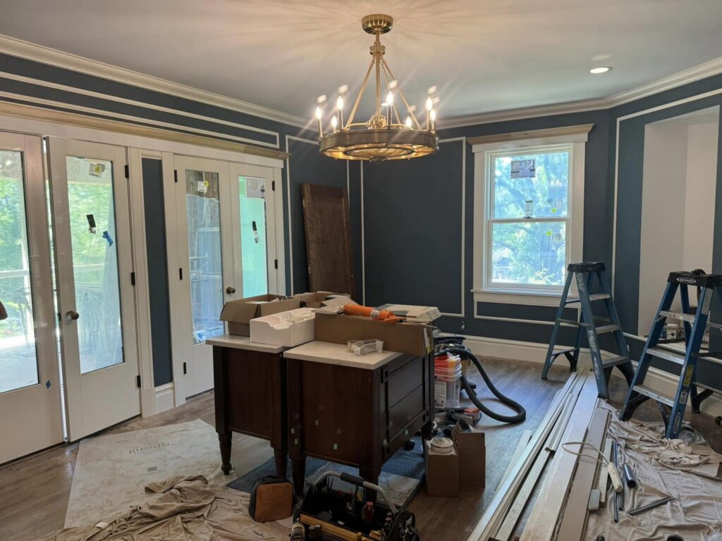A room with dark blue walls and white trim, showing painting and trim work in progress by Tribute Painting & Drywall in St. Louis, MO.