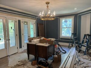 A room with dark blue walls and white trim, showing painting and trim work in progress by Tribute Painting & Drywall in St. Louis, MO.