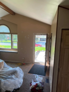 A room prepped for painting and repair work, with an open door and tools on the floor, by Honest Help in Fort Wayne, IN
