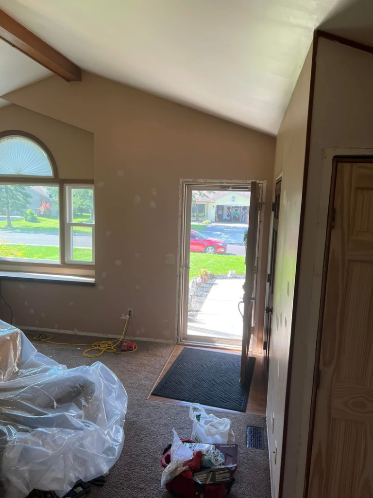 A room prepped for painting and repair work, with an open door and tools on the floor, by Honest Help in Fort Wayne, IN