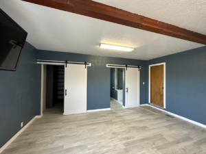 A renovated room featuring new flooring, dark blue walls, and modern barn doors installed by DSM Construction in Evanston, WY.