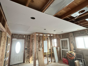 A room under renovation showing partial drywall ceiling, exposed framing, and electrical wiring by Kliesen Construction Company in Pueblo, CO.