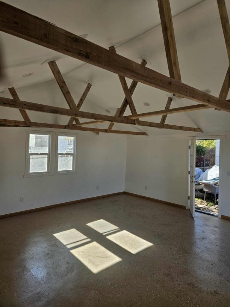 An empty room with exposed ceiling beams, indicating renovation work by Honeycomb Handyman Services in Salt Lake City, UT.
