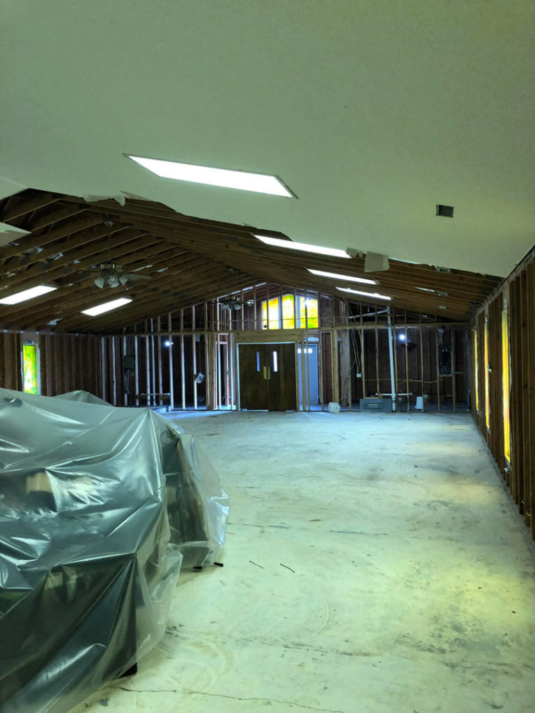 Large room undergoing renovation with exposed wall studs and ceiling removed by Rampro Construction in Rock Hill, SC