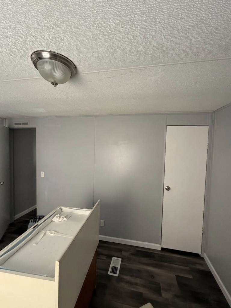 An interior room after renovation, featuring new flooring, freshly painted walls, and a ceiling light fixture by Hard Knox Handyman in Knoxville, TN.