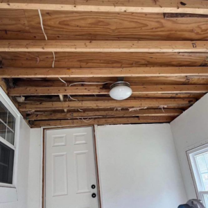A room undergoing renovation with exposed ceiling joists and an old light fixture by A 2 Z Home Services - Fairmont WV.