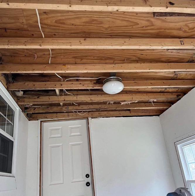 A room undergoing renovation with exposed ceiling joists and an old light fixture by A 2 Z Home Services - Fairmont WV.