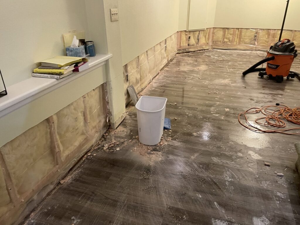 A room undergoing renovation with exposed wall studs, insulation, and a shop vacuum, showing work by RAW Renovation in Denver, CO.