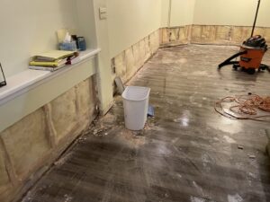 A room undergoing renovation with exposed wall studs, insulation, and a shop vacuum, showing work by RAW Renovation in Denver, CO.