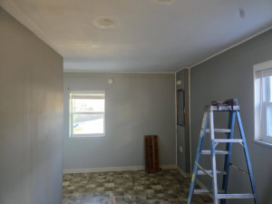 A room undergoing renovation with a ladder and tools, showing ceiling patches by Sure Can LLC Handyman Services in South Charleston, WV.