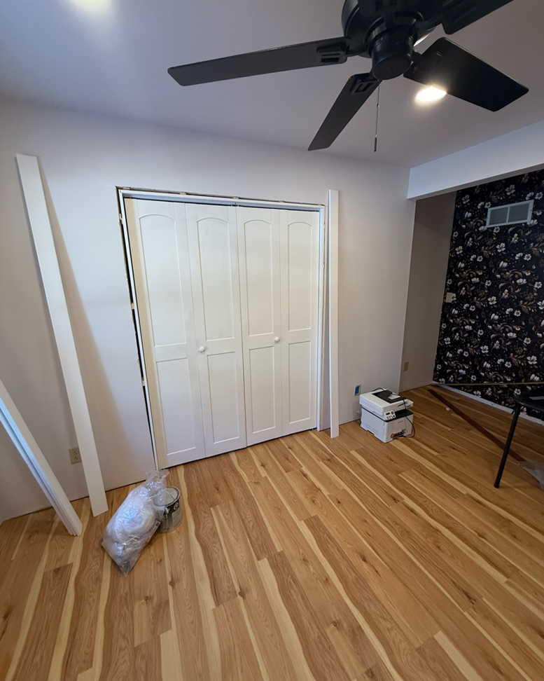 A room undergoing renovation with new hardwood flooring, bifold closet doors, and trim installation by Fix Fast Flip, LLC in Plainfield, IL.
